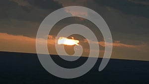 Sunset sun setting in red sky behind the clouds and dark city skyline near the Ulwatu cliff in Ulwatu Temple at Bali Indonesia