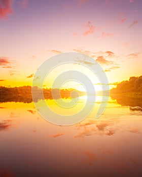 A sunset or sunrise scene over a lake or river with dramatic cloudy skies reflecting in the water on a summer evening or morning