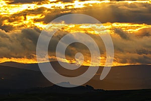 Sunset with a sunspot in a rolling hills landscape