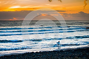 Sunset Surfer leaving cool Atlantic under a red sunset sky