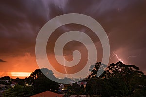 Sunset thunderstorm view from park over the city with bolts and