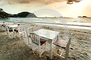 Sunset time at empty beach restaurant with wooden tables and without customers. Tropical island scene