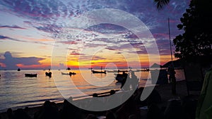 Sunset time lapse with people on the beach and boats