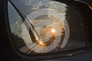 Sunset in a traffic jam on the road through the right side mirror in the car