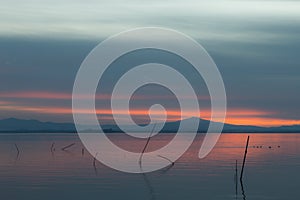 Sunset a Trasimeno lake Umbria, Italy, with fishing net poles on the foreground