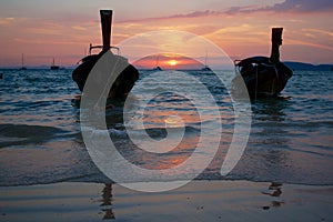 Sunset at tropical beach with traditional Thai boats