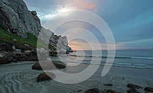 Sunset twilight colors and sand swirls at Morro Rock on the central coast of California at Morro Bay California USA