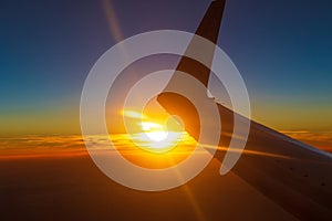 Sunset under flying airplane wing