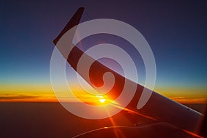 Sunset under flying airplane wing