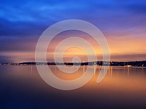 Sunset and urban lights reflected in water