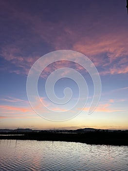 Sunset with vibrant clouds in the sky reflected in the lake below