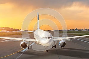 Sunset view of airplane on airport runway after landing taxiing under dramatic sky