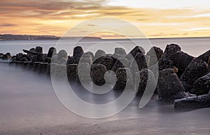 Sunset view at beach with tetrapods and long exposure water