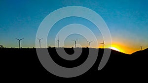 Sunset view with electric wind towers in vignette and a blue sky.