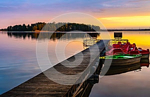Sunset view of Jezioro Selmet Wielki lake landscape with boat pier and wooded island in Sedki village in Masuria region of Poland