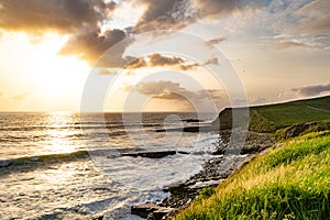 Sunset view of Mullaghmore Head with huge waves rolling ashore. Picturesque scenery with rocky coastline in evening light.