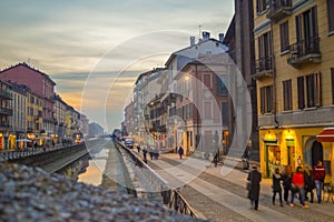 A sunset view of the Navigli canal of Milan italy with color full houses and people walking