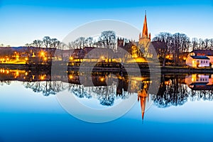 Sunset view of Nidaros cathedral reflecting on river Nidelva in Trondheim, Norway