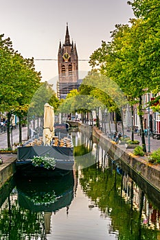 Sunset view of Oude Kerk church behind a channel in Delft, Netherlands