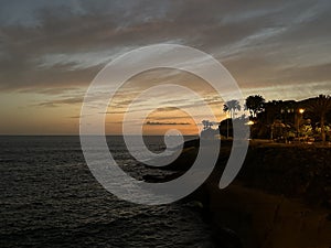 A sunset view of a Playa del Duque beach with palm trees and the ocean near Adeje, Tenerife, Canary Islands, Spain, March 2023