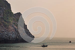 Sunset view on rock islands with fishing boat in Ha Long Bay near to Cat Ba, Vietnam