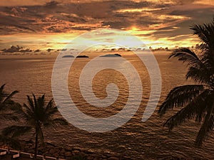 Sunset view of sea with small islands and palm tree in Sabah