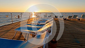 Sunset and a view of the sea and a sunbeds on a pier