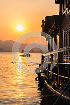 Sunset view of the West Lake in Hangzhou, China. Beautiful silhouette of a chinese boat on the lake in sunset colors