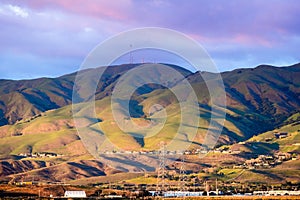 Sunset views of mountains located in South San Francisco Bay Area, with a residential neighborhood at the base of green hillsides