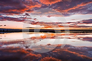 Sunset views of the tidal marshes of Alviso with colorful clouds reflected on the calm water surface, Don Edwards San Francisco