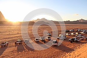 Sunset in Wadi Rum desert in Jordan with pickup trucks on sand