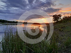 SUNSET,WATER,TREES,REFLECTION OF SUNSET ON THE PLACID WATER OF A LAKE