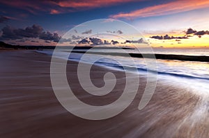 Sunset and waves at Jimbaran beach in Bali photo