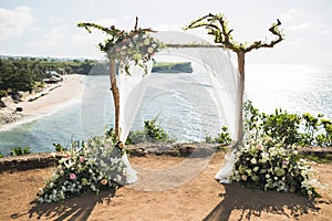 Sunset wedding ceremony arch with wooden branches on Balangan cliff in Bali