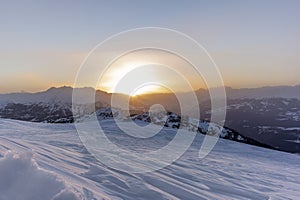 The sunset in winter during a wind storm with the snow being blown away on a peak near Lenzerheide in Switzerland