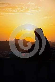 Sunset and woman. Girl against the backdrop of sunset. Orange sky and sun