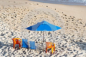 Sunshade and chairs on the beach in the strong sun of the day photo