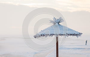 Sunshade covered with snow on the beach in the winter