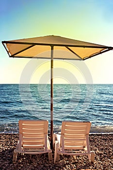 Sunshades and chaise lounges on beach. Summer seascape.