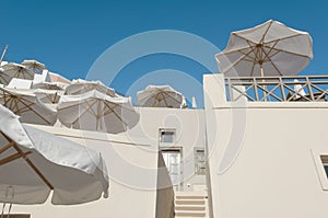 Sunshades in Greece - Santorini. White sunshades against white walls on terraced hotel outdoor area