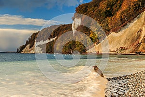 Sunshine in autumn on Ruegen with coastline with water waves