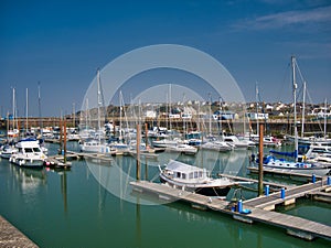 In sunshine on a calm sunny day, leisure boats moored on piers at Maryport Marina in north west Cumbria, England, UK