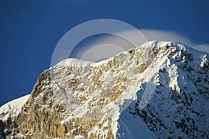 Sunshine and clouds on high mountain snow peak