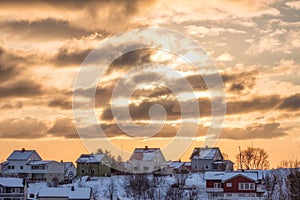 Sunshine in clouds over scandinavian fishing village with snowy