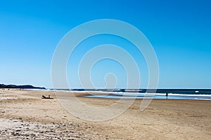 Sunshine Coast beach in Australia with unreognizable people silhouetted in the distance, including one man on a laptop