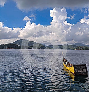 Sunshine illuminates a tranquil sea, gentle hills, and a solitary ship.