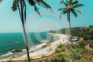 Sunshine landscape with long sandy beach and palms forest, tourist chilling in blue waves of ocean and cafes on seaside