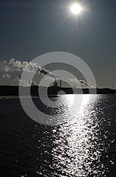 sunshine on the surface of the sea with industrial smokes in Oulu, Finland