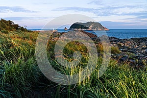 Sunshined grassland and Lighthouse during sunset at Seaseom, Seogwipo, Jeju Island, South Korea