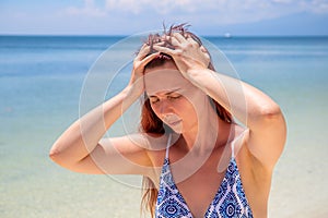 Sunstroke headache on tropic seaside during vacation. Bright sun negative impact on health. Medicine on summer photo